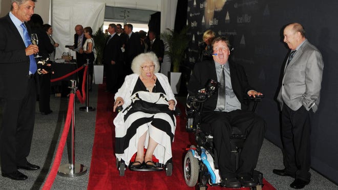 Jeanetta Holder , the quilt lady and team owner and former driver, Sam Schmidt race down the red carpet  during the Indianapolis 500 Victory Banquet  Monday  May 26, 2014 at The Indianapolis Motor Speedway