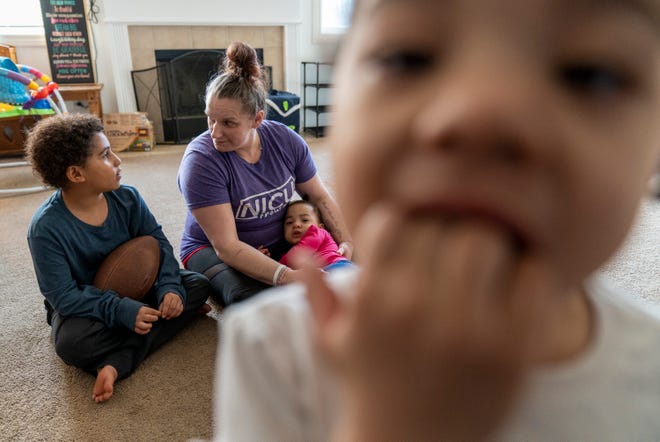 Sarayah Small peers into a camera as JJ Mullen, 7, chats with his mother Katrina Mullen, as she holds Serenitee Small on Sunday, Feb. 26, 2023, at their home in Brownsburg.