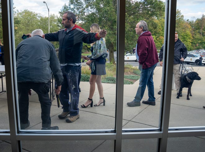 An explosives-sniffing dog and its handler check entrants, as they get metal detected outside Congregation Beth-El Zedeck, on Monday, Oct. 9, 2023. The synagogue service comes two days after the start of a potentially lengthy war involving Israel and Hamas.
