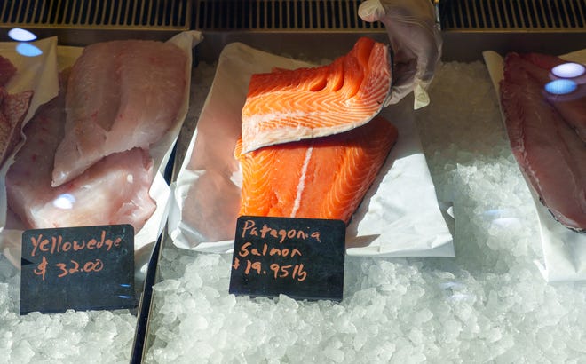 Mark Dye, store manager at Bardales Seafood Market & Wholesale, sets fresh Patagonia salmon in the display cooler Wednesday, Dec. 20, 2023, inside their Broad Ripple store.