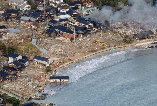 This aerial photo provided by Jiji Press shows smoke rising from a house fire (top R) along with other damage along the coast in the town of Noto, Ishikawa prefecture on Jan. 2, 2024, a day after a major 7.5 magnitude earthquake struck the Noto region in Ishikawa prefecture.