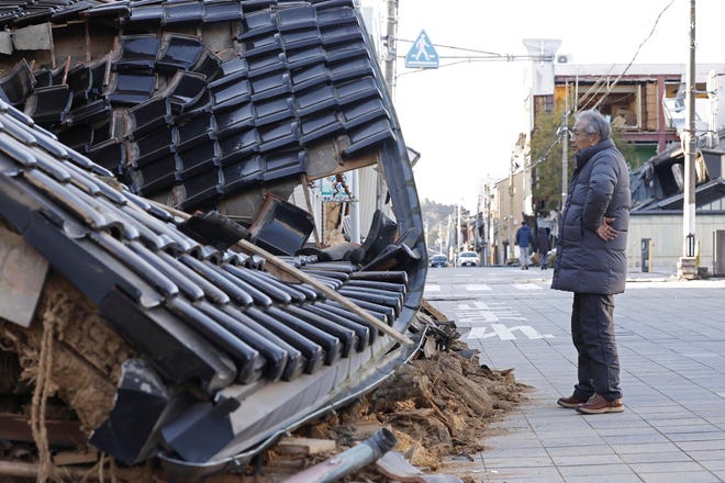 A man stands in front of a destroyed candle store following an earthquake in Nanao, Ishikawa prefecture, Japan Tuesday, Jan, 2, 2024.