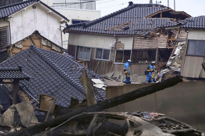 Police officers conduct a search operation at a destroyed house following an earthquake in Wajima, Ishikawa prefecture, Japan Tuesday, Jan. 2, 2024.