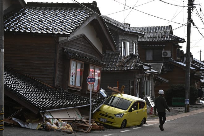 A car is seen trapped under a collapsed house in Wajima, Ishikawa prefecture on January 2, 2024, a day after a major 7.5 magnitude earthquake struck the Noto region in Ishikawa prefecture in the afternoon. Japanese rescuers battled against the clock and powerful aftershocks on January 2 to find survivors of a major earthquake that struck on New Year's Day, reportedly killing more than 20 people and leaving a trail of destruction.