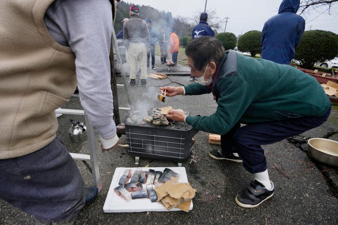 An evacuee volunteers to grill pieces of fish at a temporary evacuation center in Suzu in the Noto peninsula facing the Sea of Japan, northwest of Tokyo, Wednesday, Jan. 3, 2024, following Monday's deadly earthquake.