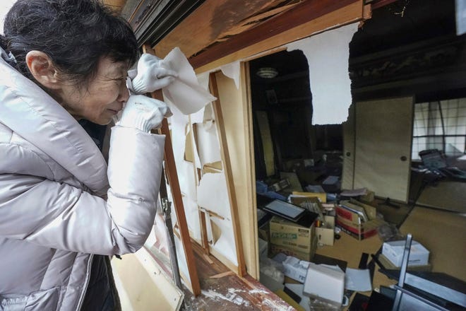 A woman looks at her destroyed house in the earthquake-hit area in Wajima, Ishikawa prefecture, Japan, Wednesday, Jan. 3, 2024. A series of powerful earthquakes that hit western Japan left multiple people dead Wednesday as rescue workers fought to save those feared trapped under the rubble of collapsed buildings.