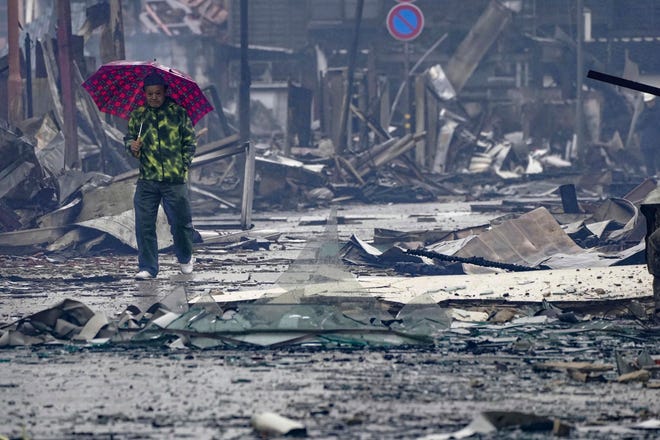 A man walks past the debris in an area hit by a fire, following earthquakes in Wajima, Ishikawa prefecture, Japan, Wednesday, Jan. 3, 2024. A series of powerful earthquakes that hit western Japan left multiple people dead Wednesday as rescue workers fought to save those feared trapped under the rubble of collapsed buildings