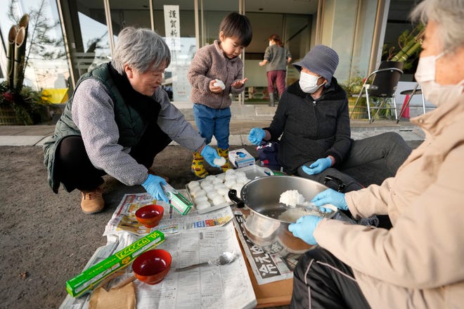 Evacuees from Monday's deadly earthquake cook rice balls at an evacuation center in Anamizu in the Noto peninsula facing the Sea of Japan, northwest of Tokyo, Thursday, Jan. 4, 2024. More soldiers have been ordered to bolster the rescue operations Thursday, providing those in need with drinking water hot meals and setting up bathing facilities after a magnitude 7.6 quake hit Ishikawa Prefecture and nearby regions Monday.