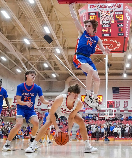 Whiteland's guard Wiatt Mclaughlin (14) leaps over Center Grove Trojans forward Will Spellman (42) on Saturday, Jan. 13, 2024, during the Johnson County finals at Center Grove High School in Greenwood. The Center Grove Trojans defeated Whiteland, 68-43.